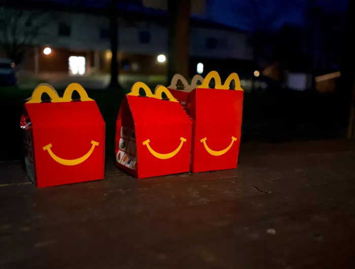 Three unopened Happy Meal boxes sitting on pavement